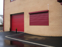 Red commercial shutters on front of building. All our commercial shutters are available in a variety of colours